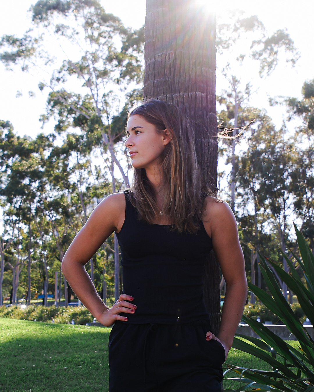 Yas leaning against a palm in golden light.